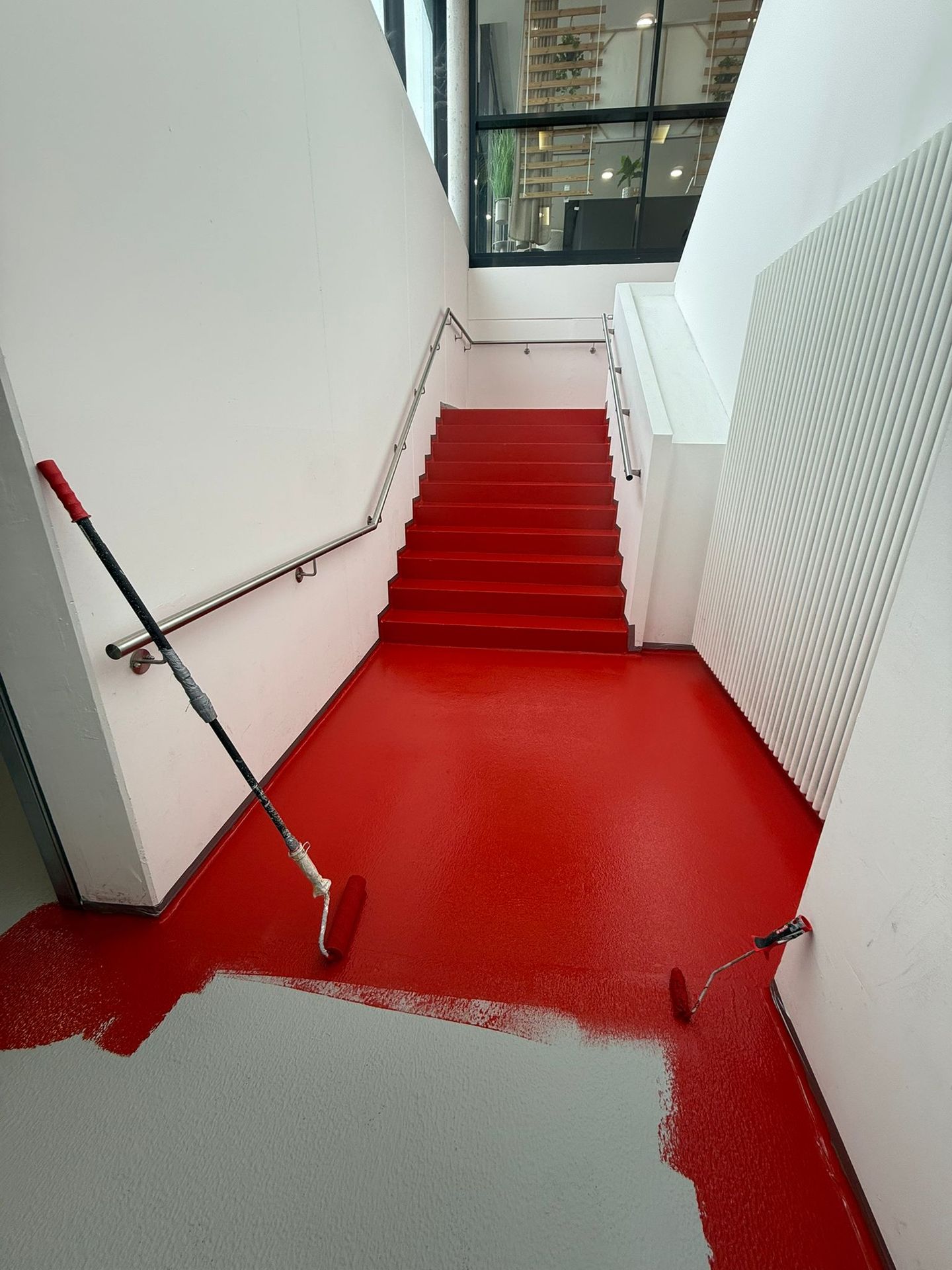 Treppenhaus während des Auftragens einer roten Bodenbeschichtung